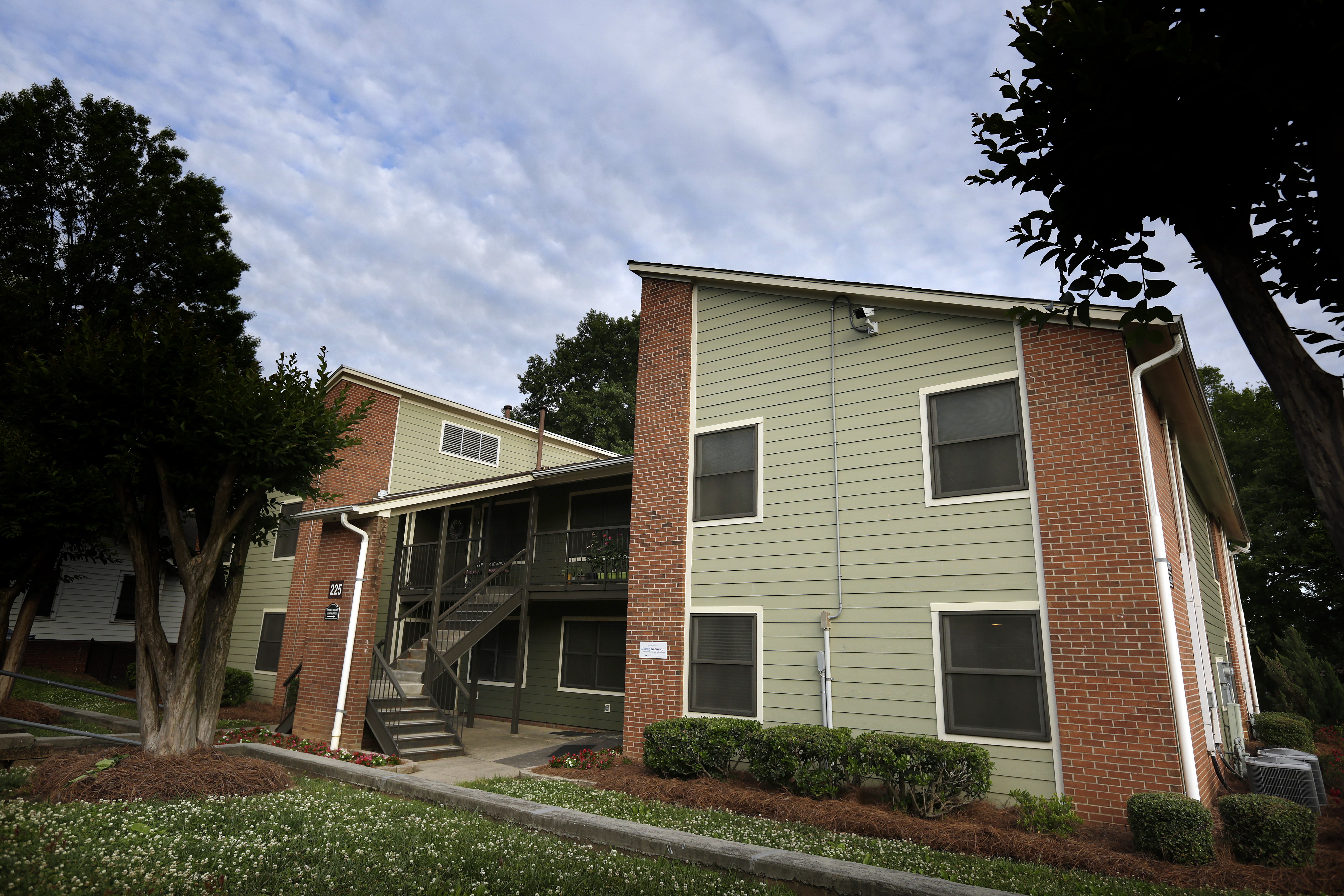 A two-story apartment building with a green siding and a brick base.